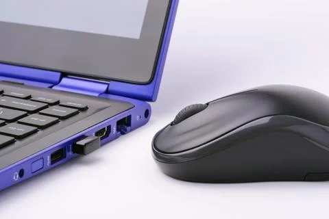 Black wireless computer mouse near the modern blue laptop Stock Photos