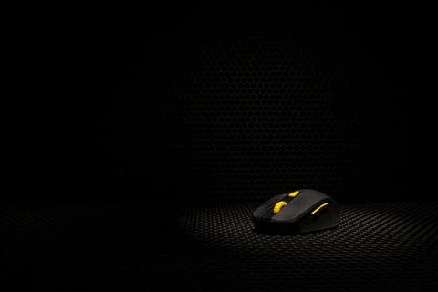 A black wireless computer mouse with yellow buttons is selectively highlighte Stock Photos