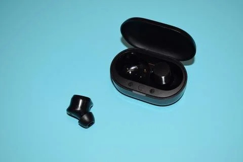 Black Wireless Earbuds and Charging Case on a Vibrant Blue Background Stock Photos