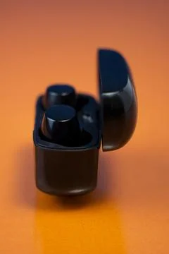 Black Wireless Earbuds with Charging Case on Orange Background Stock Photos