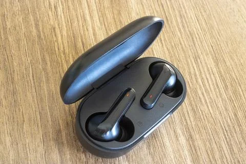 Black Wireless Earbuds Resting Inside Open Charging Case Stock Photos