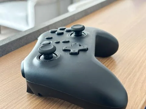 Black Wireless Gaming Controller on a Modern Wooden Desk Surface Stock Photos