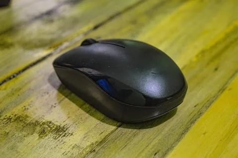A black wireless mouse on a wooden table Stock Photos