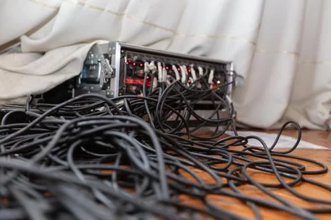 Black wires spill from a server rack in a dimly lit room during late afternoo Stock Photos