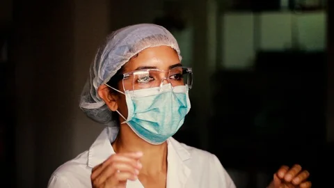 BLACK WOMAN DOCTOR, NURSE TAKES OF SAFETY GOGGLES, MASK AND CAP Stock Footage