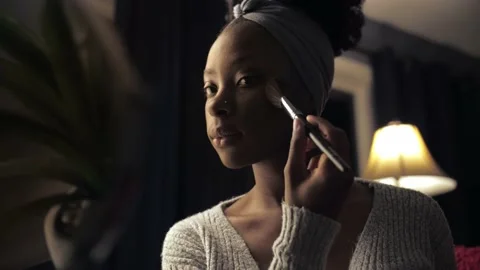 Black woman doing make up in dark room interior.African afro girl applying Stock Footage 236334888