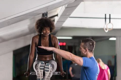 Black woman doing parallel bars Exercise with trainer Stock-Fotos