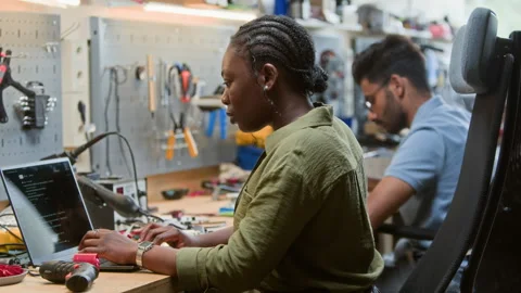 Black Woman Engineer Coding on Laptop in Robotics Workshop Stock Footage 343509214