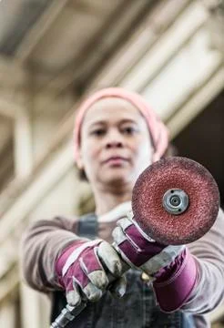 Black woman factory worker using a metal grinding tool in a sheet metal factory. Stock Photos