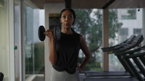 Black woman looking at the camera while using a dumbbell Stock Footage 232582840