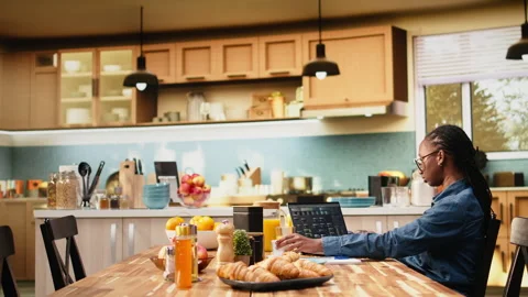Black woman programming on laptop in kitchen representing hybrid work Vídeos de archivo 344243786