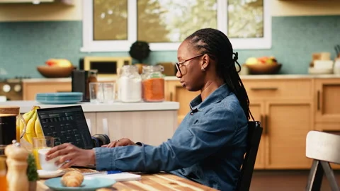 Black woman programming on laptop in kitchen representing hybrid work Vídeos de archivo 344246704
