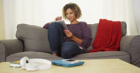 Black woman sitting on couch using tablet Video stock 44498042