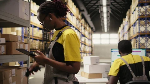 Black woman staff using a barcode scanner to process shipping labels Stock Footage 315716611