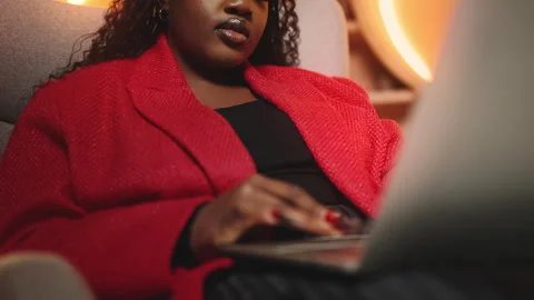 Black woman working on laptop while sitting in an armchair, freelance career Stock Footage 340766196
