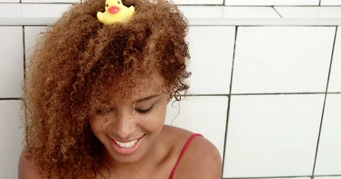 Black woman's portrait sitting in bath with a duck on her head Stock Footage 77439092