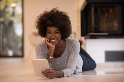 Black women using tablet computer on the floor beautiful young black women... Stock Photos
