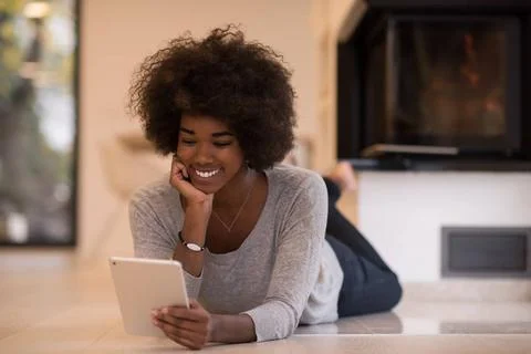 Black women using tablet computer on the floor beautiful young black women... Stock Photos