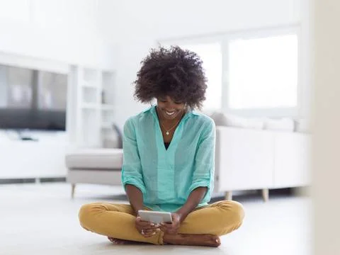 Black women using tablet computer on the floor at home beautiful young bla... Stock Photos