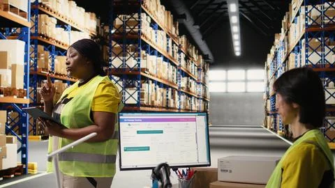 Black worker uses package tracking interface on tablet for inventory control Stock Photos
