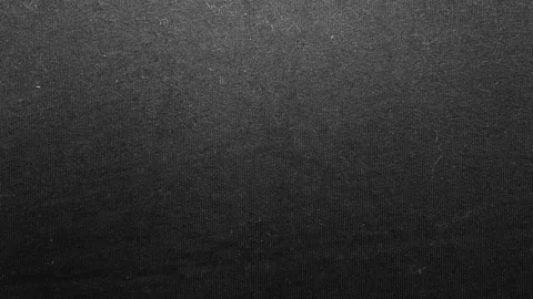 Black woven fabric texture glides past cinematic macro lens revealing moody dark Stock Footage 337025416