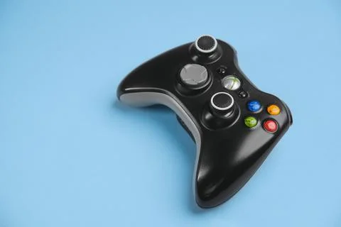 Black Xbox 360 wireless controller on blue background solid color. Stock Photos