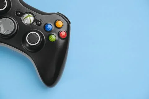 Black Xbox 360 wireless controller on blue background solid color. Stock Photos