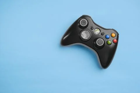 Black Xbox 360 wireless controller on blue background solid color. Stock Photos