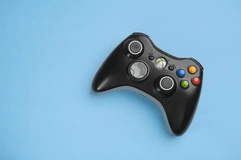 Black Xbox 360 wireless controller on blue background solid color. Stock Photos