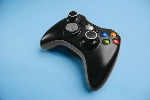 Black Xbox 360 wireless controller on blue background solid color. Stock Photos