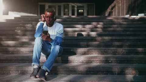 Black young man listens to music with headphones Stock Footage 155691753