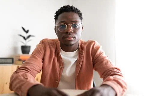 Black young man looking at camera with serious expression during video call. Stock Photos
