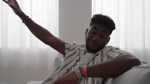 Black young man sitting on sofa and talking to camera Stock Footage 240907947