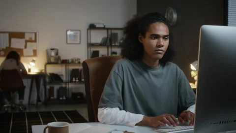 Black Young Man Working on Desktop Computer in Office at Night Stock Footage 348154198