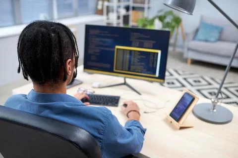 Black young man writing code while studying computer programming at home 库存照片