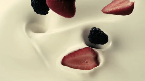 Blackberries and strawberries fall down into pouring creamy milk Stock Footage 147514026