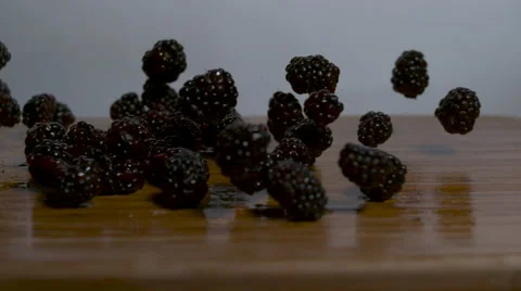 Blackberries falling and rolling onto a cutting board in slow motion - static Stock Footage 64230983
