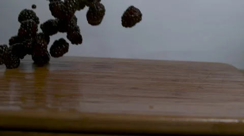 Blackberries falling and rolling onto a cutting board in slow motion Stock Footage 64235979