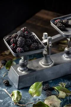 Blackberries on metal scale on rustic table with leaves and dark marble Stock Photos