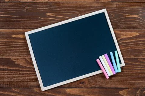 A blackboard with space for text and a set of colored crayons on a wooden Stock Photos