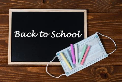A blackboard with text Back to School, set of colored crayons and a protective Stock Photos