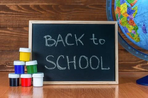 A blackboard with the text Back to School, a set of colorful paints and a globe Stock Photos