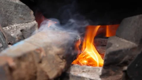 A blackened cooking pot stands over fire inside a clay stove used for traditiona Stock Footage 338001195