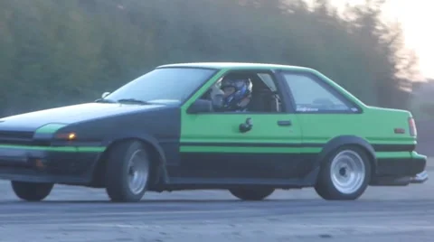Black/green car rounds corner at drifting event. - Drift Racing Stock Footage 59762222