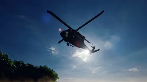 A Blackhawk military helicopter lands on a dusty road on a clear day in a Stock Footage