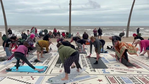 Blackpool, UK 2025 Aug 10; Yoga class performing on Tower Headland. 4k video Stock Footage 314708372