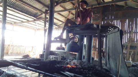Blacksmith assistant uses traditional hand belows, fire under kettle, low angle Vídeos de archivo 79838682