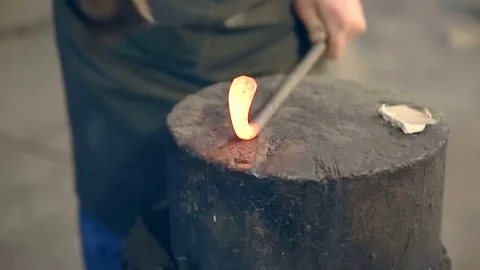 Blacksmith bend hot metal with a hammer on the anvil in the smithy Stock Footage 76399740