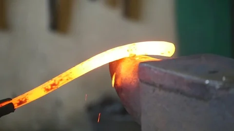 Blacksmith bends an iron hot stick with a hammer Stock Footage 78905090