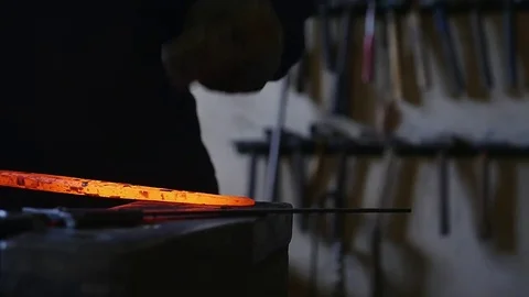 Blacksmith bends an iron hot stick with a hammer Stock Footage 78905157